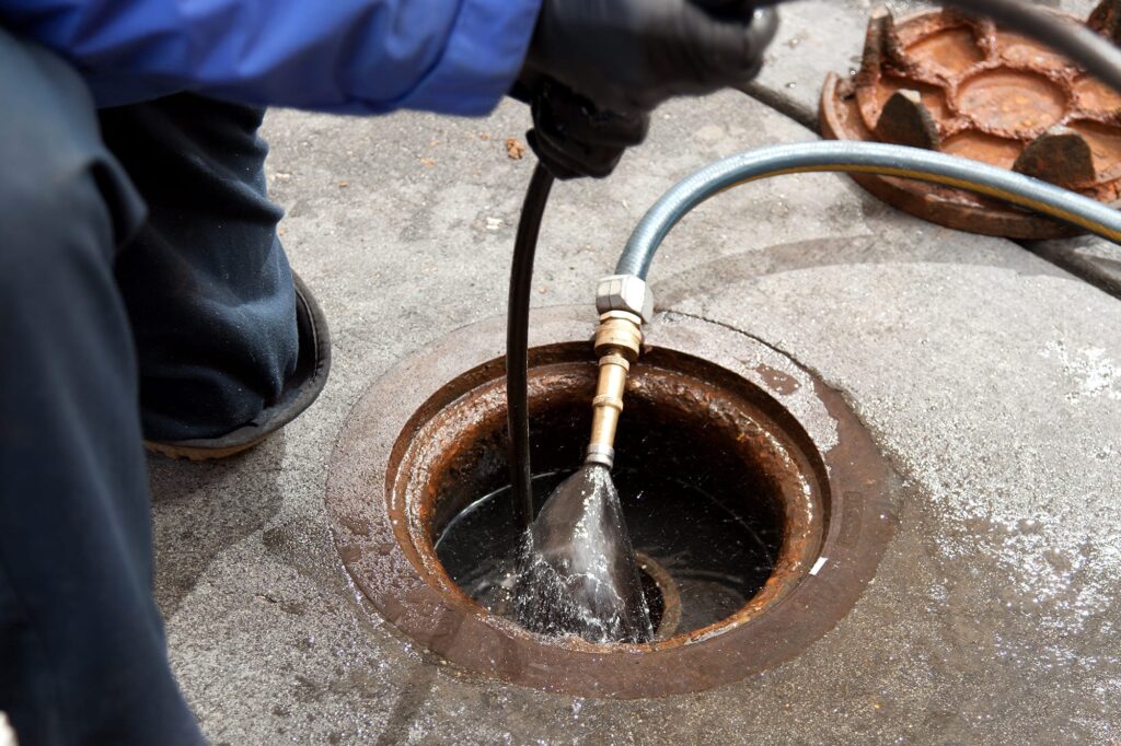 Plumber hydro jetting a sewer line through a manhole in Orlando