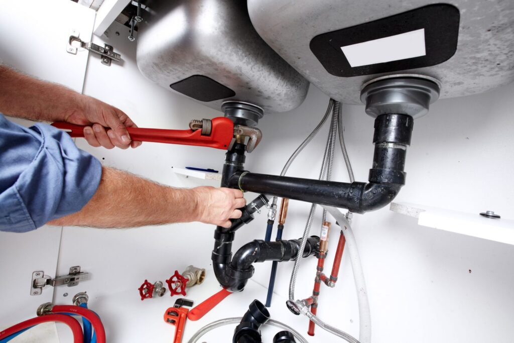 Plumber repairing drain pipes beneath a kitchen sink in Orlando