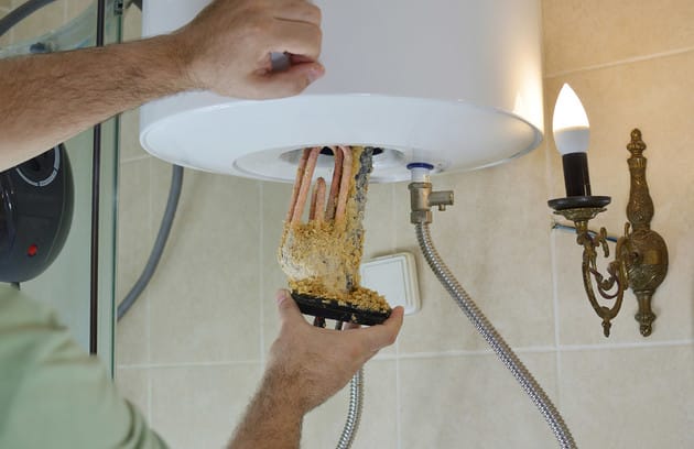 Technician removing mineral buildup from a water heater in Orlando